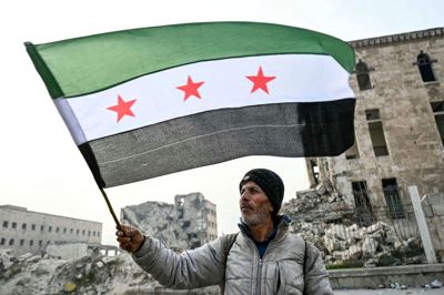 En mand går med et syrisk oppositionsflag i Aleppo, som oprørere indtog tidligt i de seneste ugers lynoffensiv, der førte til Assad-styrets fald. (Arkivfoto).