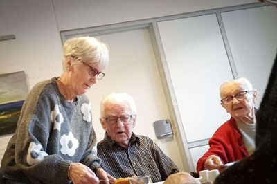 To gange om ugen er der fællesspisning for de ældre beboere på Bavnehøjcentret i Nørre Snede. Her serverer Maja Christensen dagens ret - stegte kartofler og kylling i flødesovs - for Ejnar Nielsen og Henny Nielsen. Det gør hun og Elsebeth Daugaard to gange om ugen, og tirsdag var der besøg fra den lokale EDC-ejendomsmægler og ligeledes lokale Ripevial Boliger. De to virksomheder er nemlig sponsorerne, der sikrer, at fællesspisningen, som i sin tid blev sparet væk, også kan finde sted i 2025. Foto: Kasper Malling Beck