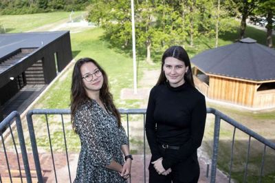 Mariya Van Geyzel (t.v.) sætter ord på nogle af de styrker et lille uddannelsessted har. To af dem ses i baggrunden i form af et nyt bålhus og multihuset, som begge danner rammen om fællesskab. Her ses hun med sin tidligere medstuderende Josephine Leer.