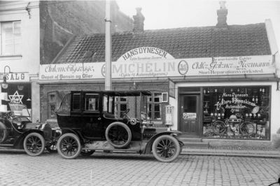 Lokalhistorisk arkiv. Den foretagsomme Hans Dynesens forretning i Bredgade omfattede så forskellige ting som cykler, symaskiner og geværer, og i 1913 er det tydeligt, at bilerne får lov at fylde stadig mere. Forretningen råder over bilforhandling af flere anerkendte mærker, over eget værksted og en udlejningsforretning. Der er olie- og benzindepot. Bemærk, at han staver bensin med s, ligesom Uno-X valgte at gøre, da selskabet blev etableret i 1950erne.