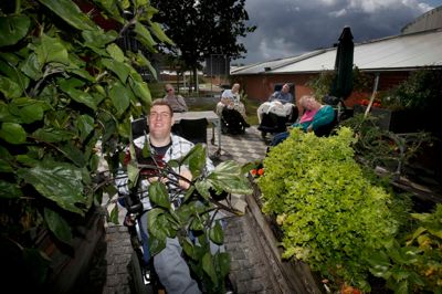 Henning Lyhne (forrest) og de andre fra Bytoftens køkken/have-gruppe nyder at sidde i den nye sansehave - i hvert fald så længe det er tørvejr. De er selv med til at passe havens grøntsager og krydderurter, som bruges i madlavningen. ?Foto: Henrik Ole Jensen