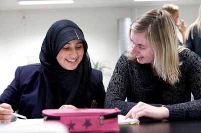Den nye lektiecafé på Brændgårdvej, »CaféKoM«, er rykket ind på det tomme bibliotek. Fatima Abbas, der går i 7. klasse på Brændgårdskolen, forsøgte midt i åbnings-tumulten at få lavet sine lektier sammen med Lisbet Holm Bogø. Foto: Henrik Ole Jensen