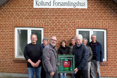 Kollund Forsamlingshus og Borgerforening fik i går en hjertestarter fra Trygfonden. Formand Sven Nordgaard (t.v.) modtog hjertestarteren af Kurt H. Jørgensen, der er ambassadør for TrygFonden i Region Midtjylland. Bagved står seks lokale borgere, som har været på kursus i at bruge hjertestarteren.?Foto: Palle Heering Nielsen