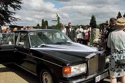 Brudeparret blev mødt med masser af ris, da de trådte ud på parkeringspladsen ved Bording Kirke. Men også af en Rolls Royce. ?Foto: Kim Kristensen