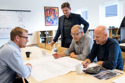 Jesper Friis Poulsen (stående), som er administrerende direktør i JFP, ser virksomhedens håndværkerafdeling som essentiel for at fastholde den rette kultur og forståelse for faget. Siddende ved bordet ses til venstre projektleder Claus Ravn og til højre tømrermester Holger Nielsen og murermester Ole Agerbo. ?Foto: Tom Laursen