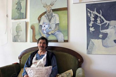 Kunstneren Allan Stochholm i sofaen med elskelige kronhjortemotiver på væggen. ?privatfoto