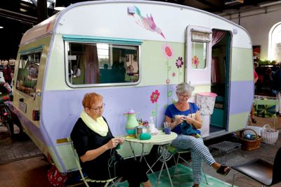 Monna Kristensen fra Brande (t.v.) og Maryan Bjarup fra Holstebro i gang med strikketøjet ved medarrangører Marianne Sommers campingvogn.
