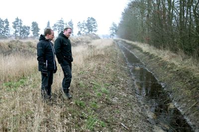 Landmand Claus Just Pedersen (t.h.) har fået dispensation til at lede vandet i Trindkær Bæk i Kølkær over et nyt forløb, så bækken ikke længere går på tværs af hans mark. På billedet ses den nye kanal, som landmanden her besigtiger sammen med formand for Herning-Ikast Landboforening, Karsten Willumsen. ?Foto: Tom Laursen