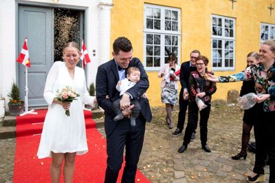 Kristina Lajgaard og Mikkel Brogaard Pedersen - og lille Rune på ni uger - blev overøst med fuglefrø og rosenblade, da parret nåede ud på den røde løber foran herregården Herningsholm efter at være blevet borgerligt viet i Riddersalen. ? Foto: Tom Laursen