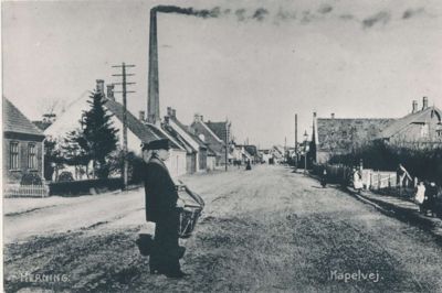 Hjulmager Engelbredt, der selv boede på Kapelvej, var også manden, som kunne traktere byens gamle brandtromme. Han kunne hyres til at gøre reklame ved at gå trommende gennem byen og gøre opmærksom på for eksempel gode tilbud på Torvet. På billedet, der formentlig er fra omkring 1905, hvor Kapelvej ændrede navn, ses Engelbredt med spindefabrikkens skorsten i baggrunden. ? Foto: Lokalhistorisk Arkiv Herning