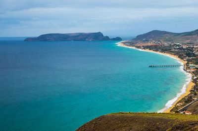 Fra et udsigtspunkt højt over havnen på Porto Santo, hvor færgen fra Funchal på Madeia lægger til (sejltid 2½ time) kan man blandt andet se den ni kilometer lange sandstrand, Praia Dourada, hvorfra man kan bade året rundt. Det grønne område for foden af bjergene øverst i billedet er Porto Santos golfbane.