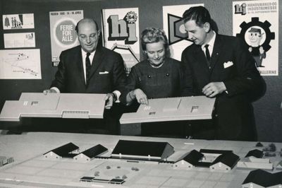 Haldirektør Kaj Zartow, fru Zartow og borgmester Jens Mathiasen står med en model over messecentret, som arkitekt K. Aa. Sejerkilde havde lavet, og hvor han altid havde et forslag til placering af den næste hal. ?Foto: Lokalhistorisk Arkiv Herning