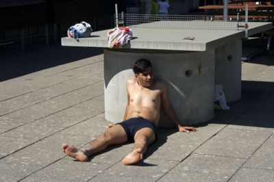En af lejrgæsterne køler sit hoved af i skyggen under Bording Friluftsbads bordtennisbord.