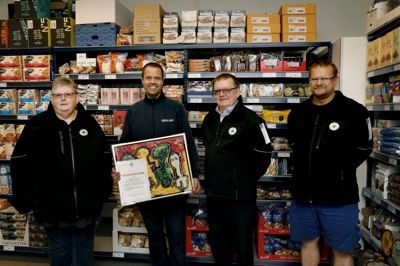 En glad købmand, Uffe Asbjørn Jensen, med det maleri og diplom, som han modtog for sit gode arbejde med at fylde julekurvene op til økonomisk dårligt stillede børnefamilier sidste år. De øvrige tre personer i Dansk Folkehjælp-trøjer er fra venstre Bodil Markmøller, Jørgen Markmøller og Brian Odsgaard. ? Foto: Henrik Ole Jensen