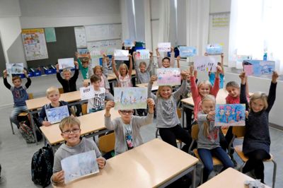 Eleverne viser deres farverige tegninger frem. På nogle vrimler det med mennesker, og der er både kæledyr og hus med, mens andre kun har tegnet den helt nære familie.