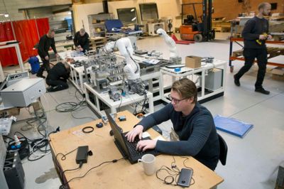 På Aalborg Universitetshospital modtager de dagligt 200 kasser med blodprøver om dagen. Når de kommer til hospitalet skal prøverne tages ud af kasserne og sorteres, og den proces er i dag manuel. Laboranterne skal klikke låg af begge de kasser, hver sending kommer i og sortere prøverne efter farve. De mange daglige kasser betyder at laboranterne for det første ikke kan følge med og for det andet at de får skader i håndled af det gentagende arbejde. Derfor har Grau Engineering for en kunde udviklet et anlæg som klarer hele processen automatisk.