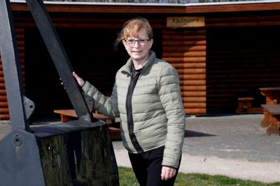 Randi Skousbøll fotograferet ved »Rådhuset« i Kølkær, hvor hun har boet i 50 år. Rådhuset er et åbent hus i rundtømmer, som er rejst på den grønne plads midt i landsbyen. Huset kaldes »Rådhuset«, fordi det er et sted, hvor byens borgere kan holde rådslagning. ?Foto: Henrik Ole Jensen
