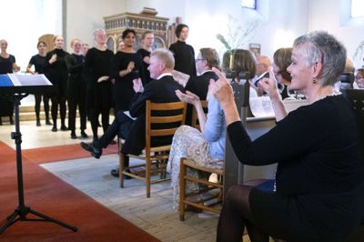 Den jyske Sangskoles kunstneriske profil, Dorte og Mads Bille, tilsyneladende andægtigt lyttende, men tag ikke fejl. Dorte Bille dirigerer koret fra midtergangen. Foto: Tom Laursen