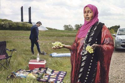 Madina Mahamoud Roble er 59 år og arbejder som social- og sundhedshjælper. Hun kom til Danmark fra Somalia som flygtning i 1994, og hun er en af de portrætterede på udstillingen »100 % Fremmed?« ligesom syriske Hozan Ibrahim, som ses i baggrunden. Billedet er fra udstillingen, der kan ses i Tinghaven overfor Herning Bibliotek frem til 2. juli. Foto: Maja Nydal Eriksen