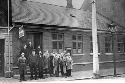Folkebladets bladhus i Østergade 25. Fotograferet omkring 1910. Ejendommen blev senere revet ned, og der blev opført nyt bladhus, som Herning Folkeblad indviede i 1969 og boede i indtil 2009, da det nuværende mediehus i Østergade 21 blev indviet. På det gamle foto er hele Herning Folkeblads personale fotograferet foran bladets kontor i Østergade. I døren med bowlerhat ses avisens daværende ejer L.V. Bendixen. Foto: Herning Folkeblad