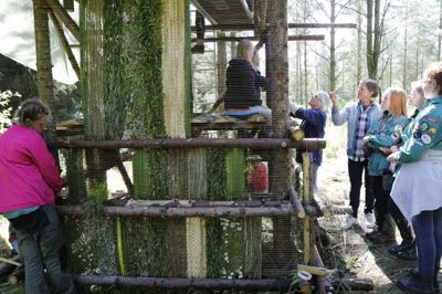 Der er blevet vævet og arbejdet på udkigstårnet hos Skovsnogen hele ugen. Det er kunstnerne Pernille Bøggild og Lisbeth Bank, derfået ideen til tårnet, som er blevet opført af granrafter. De har derefter sammen med pigerne beklædt tårnets sider med blade og grene fra skoven, som de har vævet ind i konstruktionen. foto: Henrik Ole Jensen henrik ole jensen