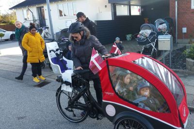 Dagplejer Jytte Nørgaard med den nye ladcykel. Børnene kan sidde beskyttet mod vind og vejr, men stadig kigge ud, når de skal ud i den natur, der bliver længere og længere ud til, efterhånden som Tjørring vokser. I den gule frakke er det Kamilla Lorraine og bag hende Katrine Skovsted, der står bag indsamlingen til ladcyklen. foto: jesper wind