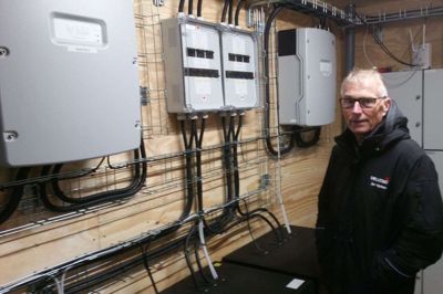 Projektchef Jan Kjeldsen ved anlægget, der opsamler strømmen fra solcellerne. Batterierne kan lades op på en halv time og rummer strøm nok til at holde bebyggelsen kørende, til solen står op igen. foto: jesper wind