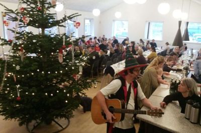 Kaj Christensen med guitar og hat får en snak ved baren med Tina Thomsen fra festudvalget i Fasterholt, inden han med sin duo »Kajseren & Troldmanden« skal underholde ved juletræsfesten i Fasterholt. foto: jesper wind