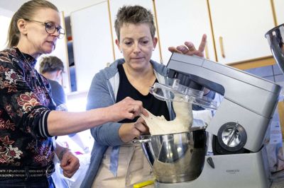 Astrid Hvam Daugaard (t.v.) fra Skibbild-Nøvling og veninden Lotte Kirk Mortensen fra Kølkær mærker på dejen for at undersøge, om teksturen er rigtig. Ifølge underviseren på bagekurset, Henrik Merstrand, skal den føles nogenlunde lige så elastisk som tyggegummi. Foto: Tom Laursen