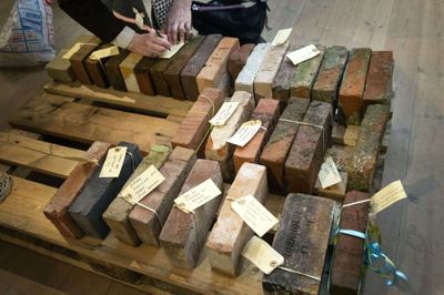 I forbindelsen åbningsforedraget med forfatteren Tor Nørretranders tilbage i marts medbragte tilhørerne brugte mursten og skrev stenens forhistorie ned på sedler. Med genåbning af udstillingen håber kunsteren på mange flere murstens-donationer fra lokale. Foto: Tom Laursen