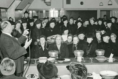 Forbruget af gas blev allerede begrænset i 1939, og under krigen blev der holdt foredrag om, hvorledes man kunne spare på gassen. Det skete også i Herning, som vist på billedet, der dog er fra Aalborg Husmoderforenings arrangement. Gasrationeringen blev først ophævet i 1948. Foto: Frihedsmuseet, illustration fra bogen