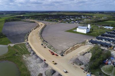 Den to kilometer lange vejstrækning fra Gullstrup mod Tjørring skærer sig vej fremad gennem landskabet. Til højre ses de nye rækkehuse på Nordskrænten og Gullestrup Kirke. Vejen skal ramme Gilmosevej i Tjørring. Foto: Flemming Hansen