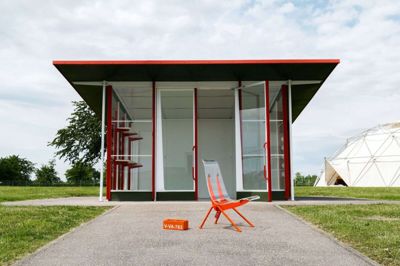 Prouvé tegnede den seriefremstillede tankstation i 1953, som nu kan ses på Vitra Design Museum, sammen med sin bror. Foran ses stolen Antony. Denne udgave er en bearbejdning af designeren Virgil Abloh, som erstattede træsædet med plexiglas og gav den et ordentligt skud orange lak. Foto: Pr-foto/Vitra.com