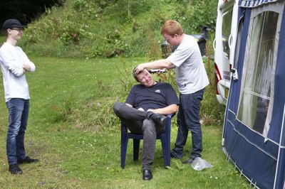 Leif Hove Nielsen får en hurtig haircut af sin søn, Tobias Hove Nielsen, mens Rasmus Bach Nielsen kigger til. Leif Hove Nielsen driver soldaterhjemmet ved kasernen i Aalborg. Her har Rasmus Bach Nielsen tidligere været ansat. Foto: Tom Laursen