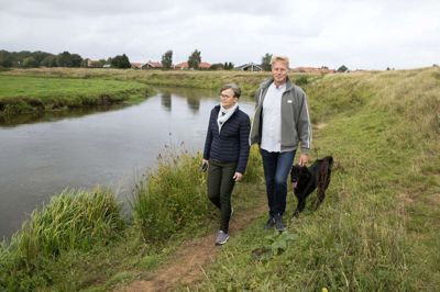 Dorte og Allan West har Skjern Å i baghaven og går ofte ture med hunden Luna i det naturskønne område. Parret har boet i byen i 22 år, og de har besluttet at flytte til Herning, efter at hun er blevet valgt til borgmesterkandidat. foto: Tom laursen