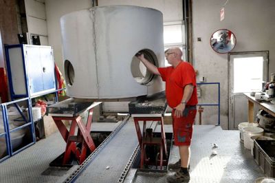 Saksebordet på produktionslinjen på Ikast Betonvarefabrik løfter beton-brøndbundene op, så Martin Toft Kristensen i en fornuftig arbejdsstilling kan fjerne flamingoresterne i de nederste huller. Foto: Flemming Hansen