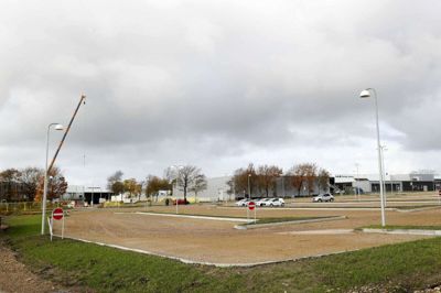 Den tidligere parkeringsplads for lastbiler over for Herning Isstadion er blevet lavet om til p-plads for biler og har fået flot blåt og gult lys i lamperne. Brændgårdvejs nye forløb skal løbe lige syd for pladsen. Foto: Flemming Hansen
