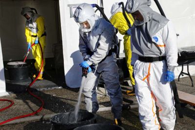 De store baljer på jorden er til gummistøvlerne. Derefter går folkene ind i teltet, hvor deres dragter bliver rengjort. Foto: Henrik Ole Jensen