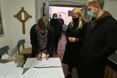 Hanne Simonsen sørger for at fordele deltagerne på bænkerækkerne til de forskellige gudstjenester. Mikael Korsgaard og Frederikke Friis skal have syv billetter til Frederikke Friis’ familie. Foto: Henrik Lind Jørgensen