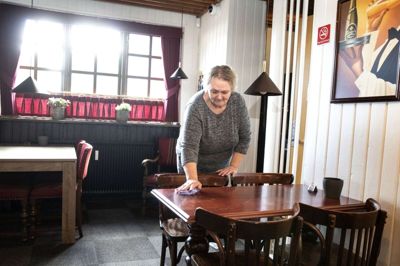 Der er indført rygeforbud i en del af Pub’en, så der også er plads til de gæster, som ikke bryder sig om tobakståger. Bordet, som Jette Dybdahl Christensen tørrer af, har oprindeligt stået i Hotel Vildbjergs krostue, men er blevet doneret til Pub’en. Foto: Tom Laursen