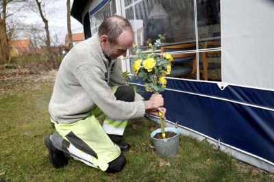 Allan Lauridsen får pyntet op foran sit fortelt med nogle blomster i årstidens farver. Det er en gave, der har ligget et stykke tid. De er af plastik. Foto: FLemming Hansen
