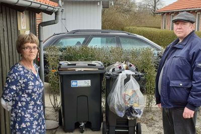 Laila Gammelgård og Daniel Ekbøl ved de to skraldespande, som otte lejemål på Friskolevej i Fasterholt skal deles om. Skraldespanden til pap og papir kan følge med endnu. Til højre er det skraldespanden til plastik, metal og kartoner. Den bliver hurtigt fyldt. Foto: Jesper Wind