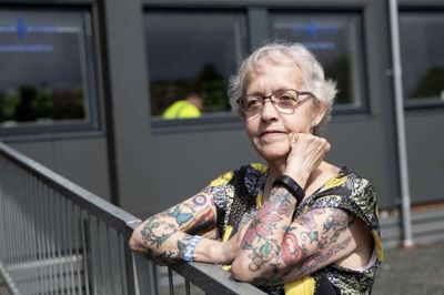 En sommerfugl, blomster, en delfin, et øje og teksten: »Mange mennesker vil gå ind og ud af dit liv, men kun sande venner efterlader fodspor i dit hjerte«. - Den, synes jeg, er så sød, siger Anne Viese, der har omkring 75 tatoveringer rundt omkring på kroppen. Hun har også flere tatoveringer, som Blå Kors Varmestues brugere har tegnet til hende igennem de 20 år, hun har været frivillig. Søndag 1. august skal hun fejres i varmestuen. Foto: Tom Laursen