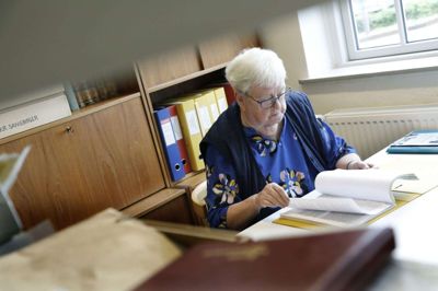 Jonna Kristensen har drevet trykkeri-virksomhed, så hun kan sagtens betjene en computer. Hun vil dog helst have fingrene i dem, der hedder Apple, og derfor holder hun sig også gerne til den analoge del af arkivarbejdet. Foto: Henrik Ole Jensen