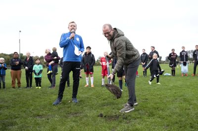 Ulrich Bak-Brinch fik lov til at svinge spaden ved det første spadestik til den nye kunstbane ved Herning KFUM Fodbold, mens klubformand Toke Juul i blå klubtrøje så på. Foto: Tom Laursen