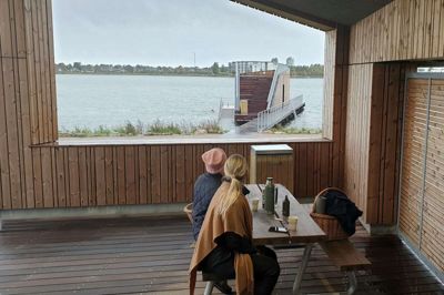 Tina Tranberg Haugaard og Mette Vedel Madsen har fundet ly for regnen med medbragt kaffe efter en tur i sø og sauna.