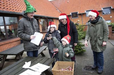 Her ved post et hjælper brødrene Sebastian og Christoffer Mortensen hinanden med at fiske et indpakket bogstav op fra kurven. Forældrene Henrik Mortensen og Sarah Bourgeois ser til sammen med farmor Karen Mortensen. Der var et »J« af pap under papiret, og det blev det første bogstav i løsningen »julefred«. Foto: Tom Laursen