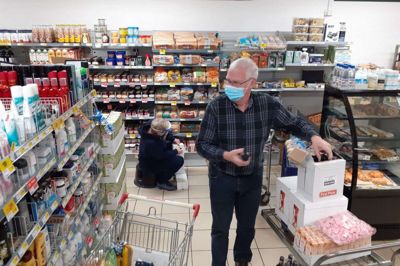 Jørgen Andersen hjælper som frivillig ikke kun med at sætte varer på plads. Han hjælper også med at føre butikkens regnskab. Bag Jørgen Andersen er det Anni Marie Larsen, der sætter ugens leverancer af brød og kiks på plads. Foto: Jesper Wind