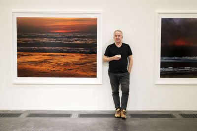 Henrik Saxgren ved siden af fotografiet, der har fået titlen »Mors solnedgang«. Redaktøren brokkede sig i øvrigt til at begynde med over titlen, fordi han læste det som øen Mors, der ikke regnes for en del af vestkysten. Foto: Jørn Deleuran