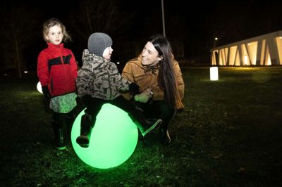 Lillebror Alexander på snart to år kunne sidde på en af lamperne, der skiftede farve. På trods af mørket stod skuffelsen malet i ansigterne på familien fra Vorgod-Barde, som havde kørt til Videbæk for at se det oplyste Videbæk Anlæg. Mor Christina Nielsen og datteren Isabella prøvede alligevel at få det bedste ud af turen. Foto: Tom Laursen